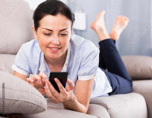 Young glad woman lying with mobile phone photo