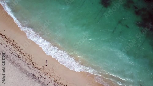 overhead aerial drone view looking down on beach and shoreline, with a man setting up his kitesurfing equipment in Kaliantan