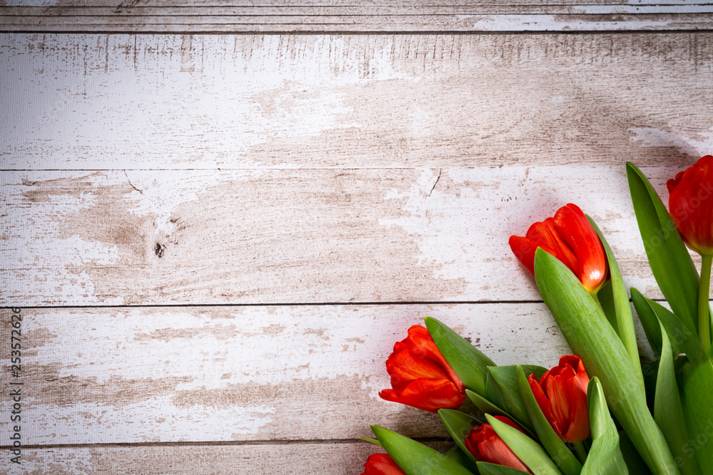 Naklejka premium Czerwone tulipany na drewnianym tle