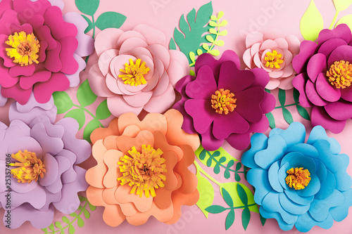 top view of paper colorful flowers and leaves on pink background