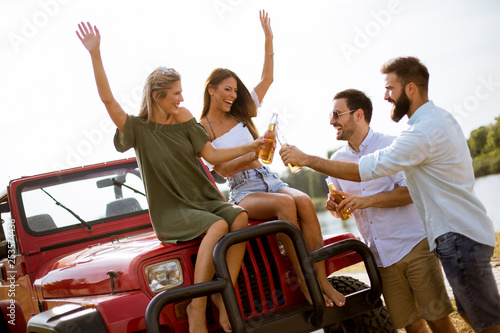 Young people drinking and having fun by car outdoor at hot summer day © BGStock72