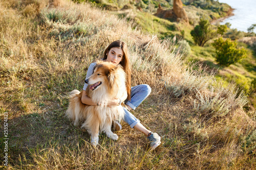 young beautiful woman walking with collie dog.