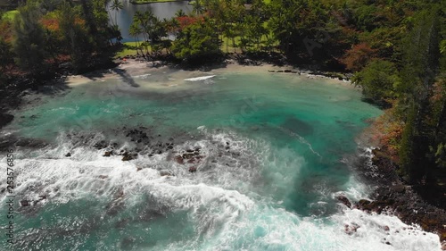 Aerial of shipman beach, a beautiful hidden cove on the island of Hawaii. Perfect ultra blue water with surrounding black and white sand mix beach :) photo