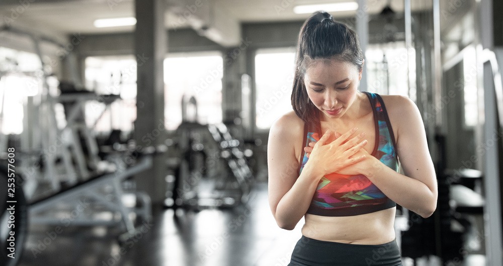 Young Asian woman clutching her chest from acute pain. Heart attack symptoms. Health care concept Young Asian woman clutching her chest from acute pain. Heart attack symptoms. Health care concept