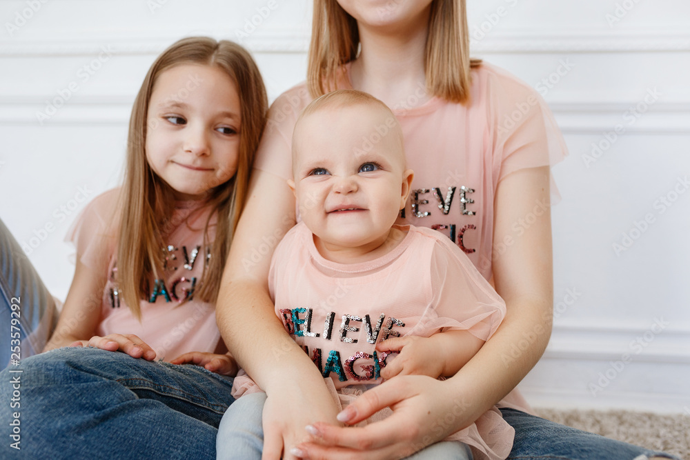 Light family series. Three sisters on a white background, dressed in funny  t-shirts and jeans Stock Photo | Adobe Stock