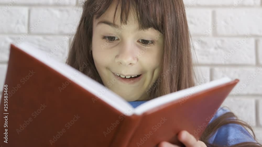 Portrait of a happy child with a book. A cute girl rejoices at the book she has read. Portrait of a happy child with a book. A cute girl rejoices at the book she has read.