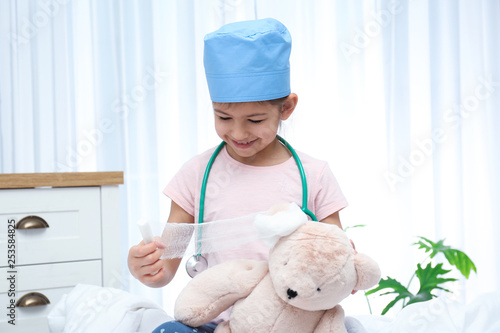 Cute child playing doctor with stuffed toy in hospital ward