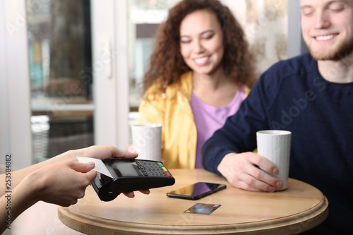 Clients using credit card machine for non cash payment in cafe photo