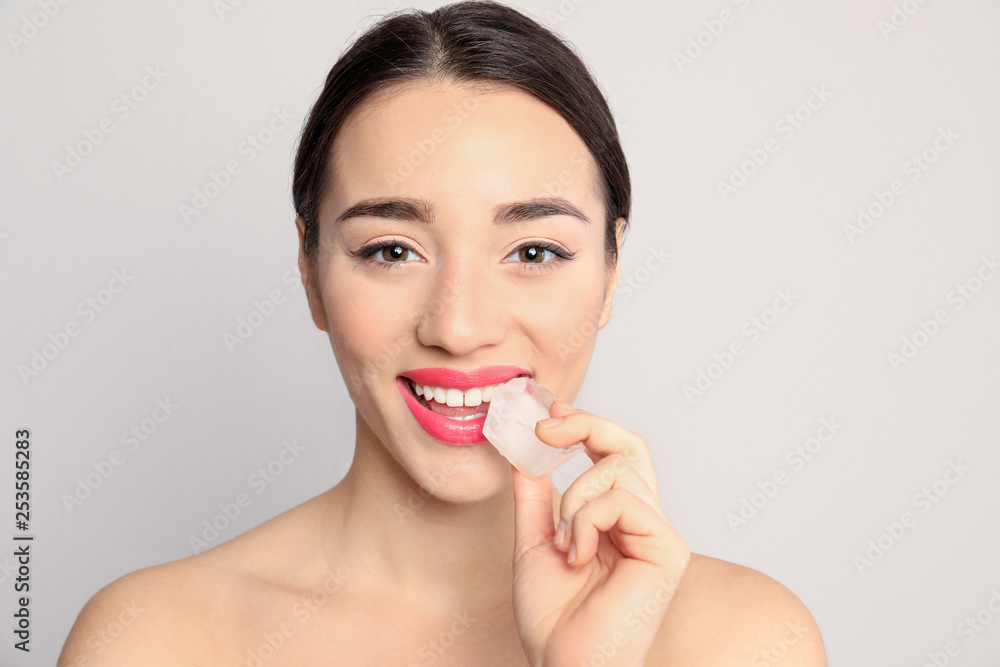 Young woman with ice cube on light background Young woman with ice cube on light background