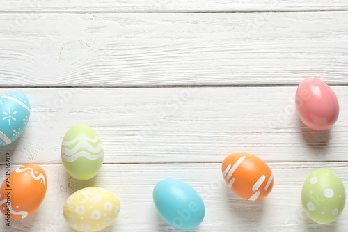 Flat lay composition of painted Easter eggs on wooden background, space for text