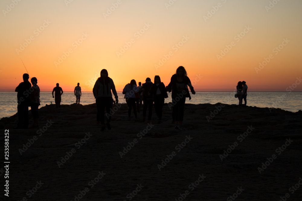 Silhouette of group of people watching the sunset on the sea