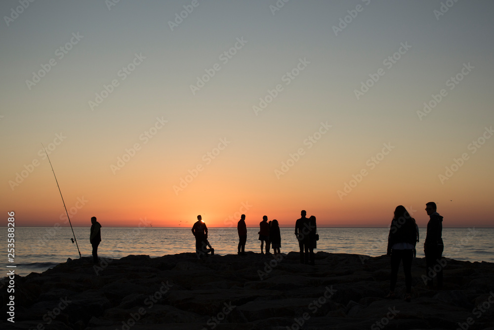 Silhouette of group of people watching the sunset on the sea