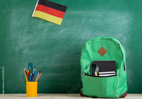 backpack, flag of the Germany, school supplies and notebooks on the background of the blackboard photo