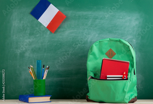 backpack, flag of the France, book and school supplies on the background of the blackboard photo