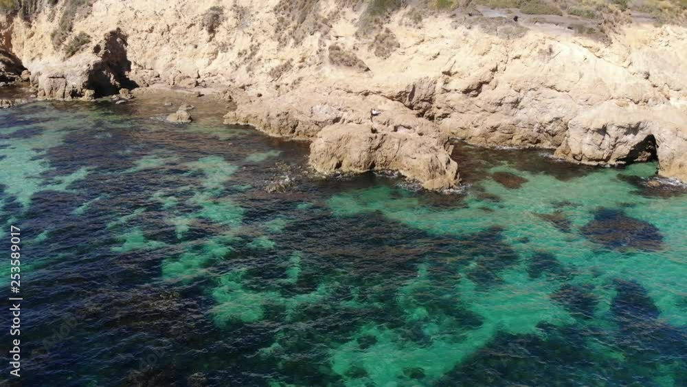 Drone zoom out of two people sitting on a rocky cliff over the clear blue ocean water near Mount Martha, Melbourne Drone zoom out of two people sitting on a rocky cliff over the clear blue ocean water near Mount Martha, Melbourne