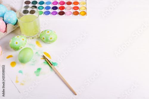 Hand painted Easter eggs, paints and brushes on a white table. Preparation for the holiday.