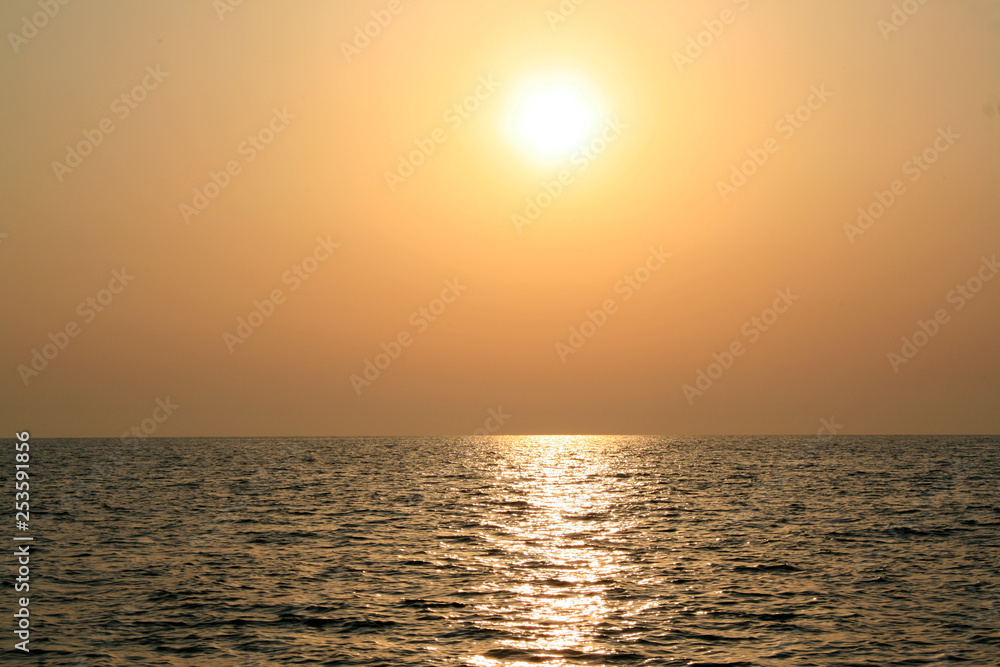 Beautiful sunrise cloudscape over sea background. Sun rays beaming through picturesque clouds
