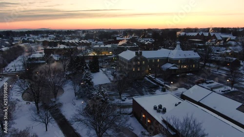 Sun setting over snow covered town of Lititz, PA, Aerial push forward 4k photo