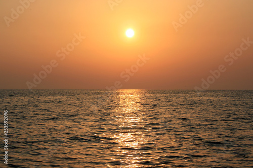 Beautiful sunrise cloudscape over sea background. Sun rays beaming through picturesque clouds
