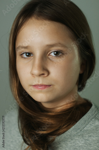 portrait of a eyed opend teen girl camly looking into the camera over green-grey plain background