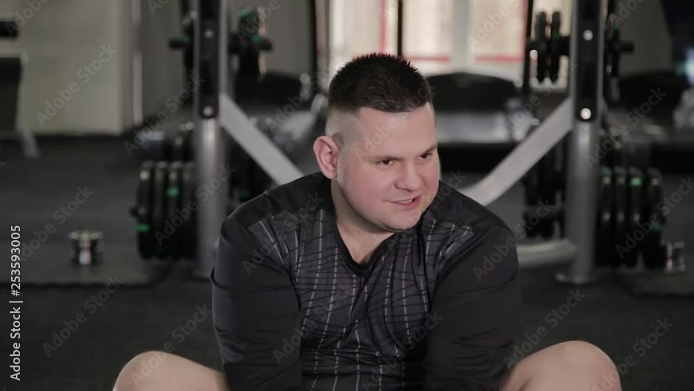 Fat man doing stretching on the floor in the gym. Fat man doing stretching on the floor in the gym.