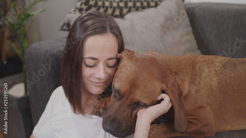 Young woman pets her dog while relaxing in the living room