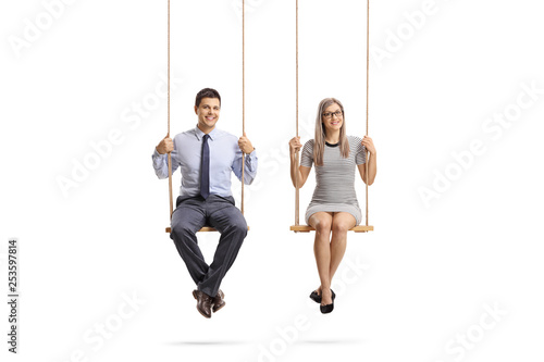 Young man and woman sitting on a swing and smiling at the camera
