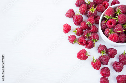 Sprinkled raspberries on white background. Ripe raspberries with copy space for text. Raspberry on a white background. Top view. Various fresh summer fruits. Background of red berries.