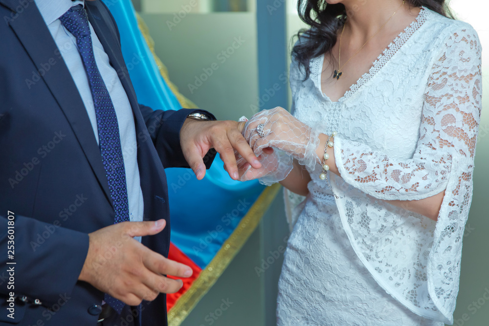 Naklejka premium Wedding. The girl in a white dress and a guy in a suit . The groom puts the ring on the bride . The process of marriage and exchange rings.