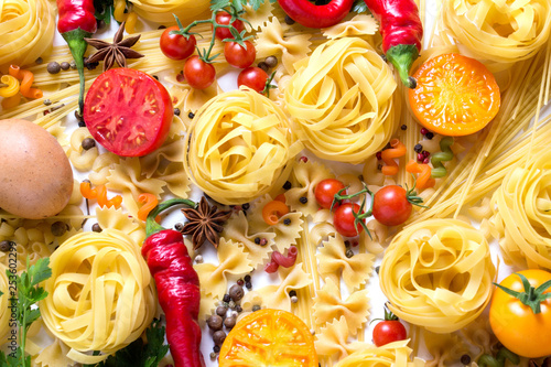 Italian pasta of various kinds with spices, red hot pepper, chicken eggs, yellow and red tomatoes on a white background. Concept cooking Italian pasta and sauce