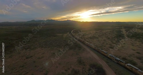 Aerial backwards dolly, showing a Train in Yuma, Arizona in stunning landscape during golden hour.