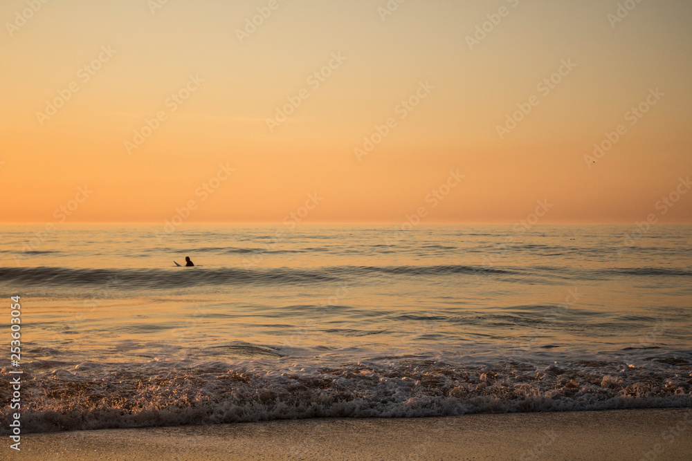 Surfer surfing in the sea, during a sunset