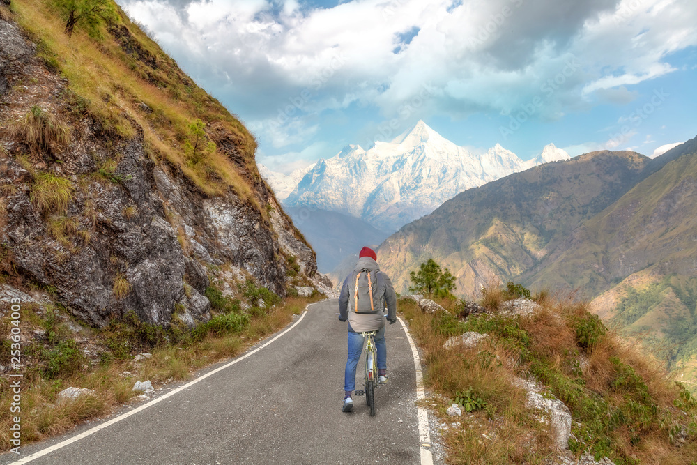 Male tourist cyclist enjoy a ride through scenic mountain road with view of Himalaya range at Munsiyari Uttarakhand India.