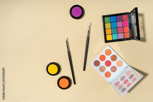 Set of brushes and eyeshadows on a yellow background