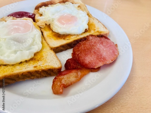 Cooked breakfast with fried eggs served on toast with bacon