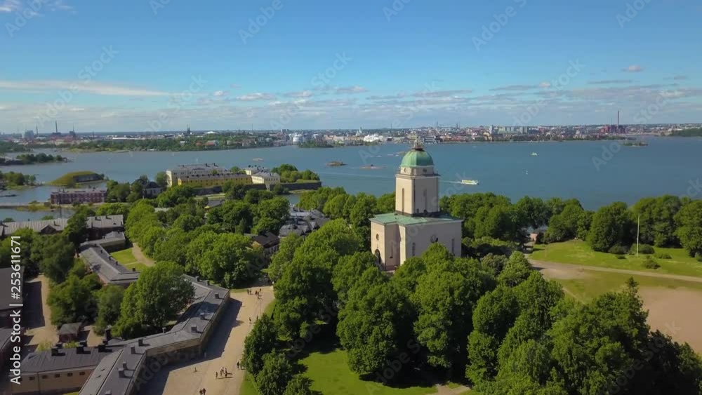 Aerial, drone shot, over buildings and the suomenlinna church, rising towards the capital cityscape, on a sunny, summer day, in Helsinki, Finland Aerial, drone shot, over buildings and the suomenlinna church, rising towards the capital cityscape, on a sunny, summer day, in Helsinki, Finland