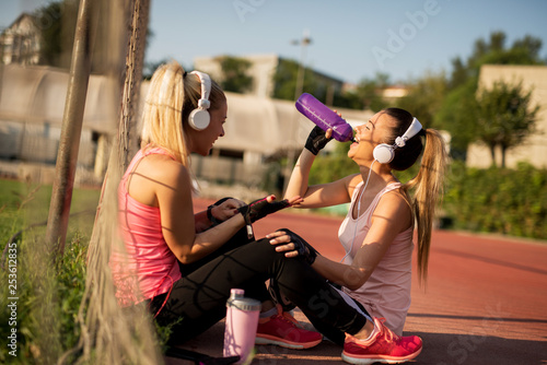 Fototapeta Naklejka Na Ścianę i Meble -  Music and fitness. Young women in sports wear with headphones exercising