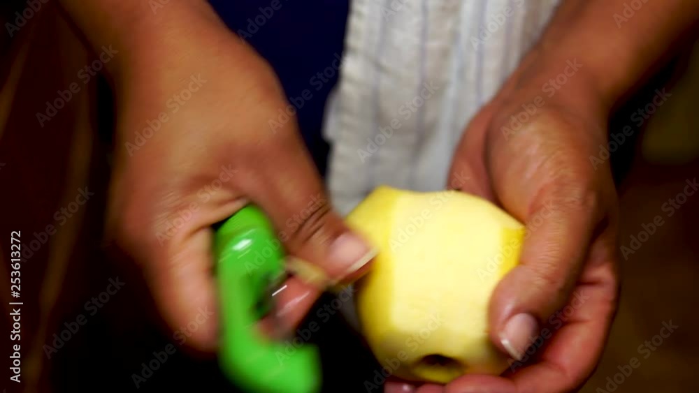 Close Up, Woman peeling yellow apple with green peeler Close Up, Woman peeling yellow apple with green peeler