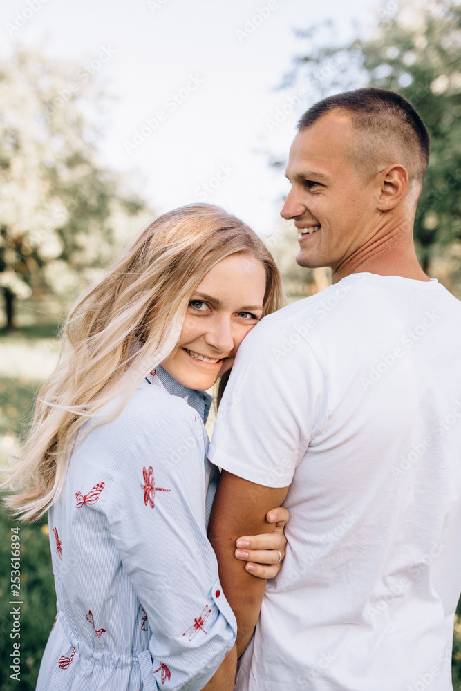 Fototapeta premium Portrait happy young smiling couple in love over flowering spring garden
