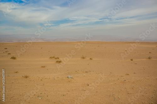 idyllic desert scenery landscape with yellow sand and horizontal board line with cloudy blue sky