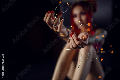 Attractive positive girl holding a garland in her hands and looking at the camera.