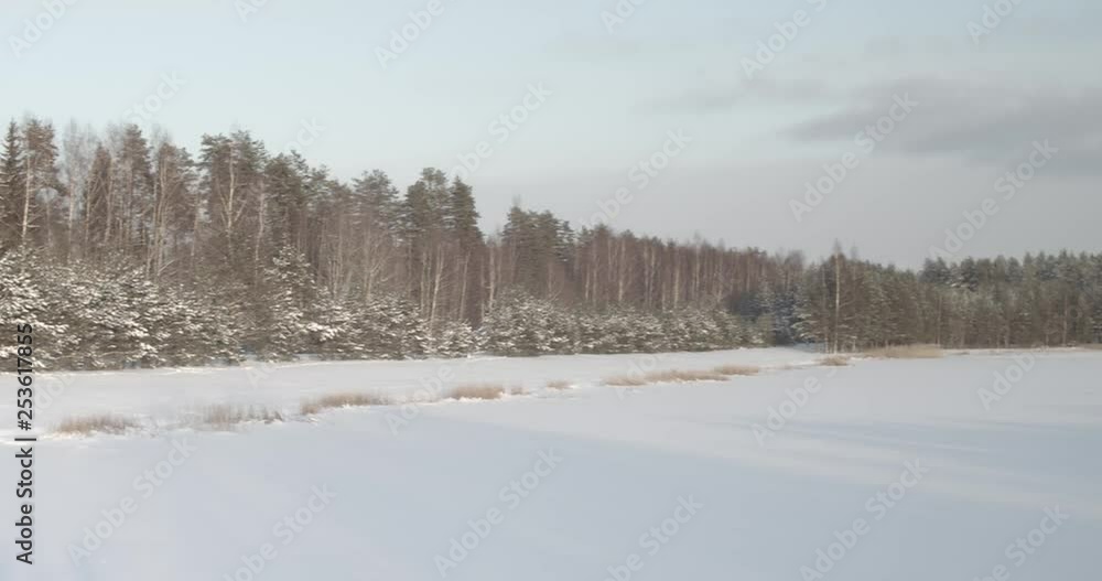 A wide shot that slowly pans to the right showing a small farmhouse and rural field surrounded by a forest of trees all smothered in freshly fallen and glistening white snow. A wide shot that slowly pans to the right showing a small farmhouse and rural field surrounded by a forest of trees all smothered in freshly fallen and glistening white snow.