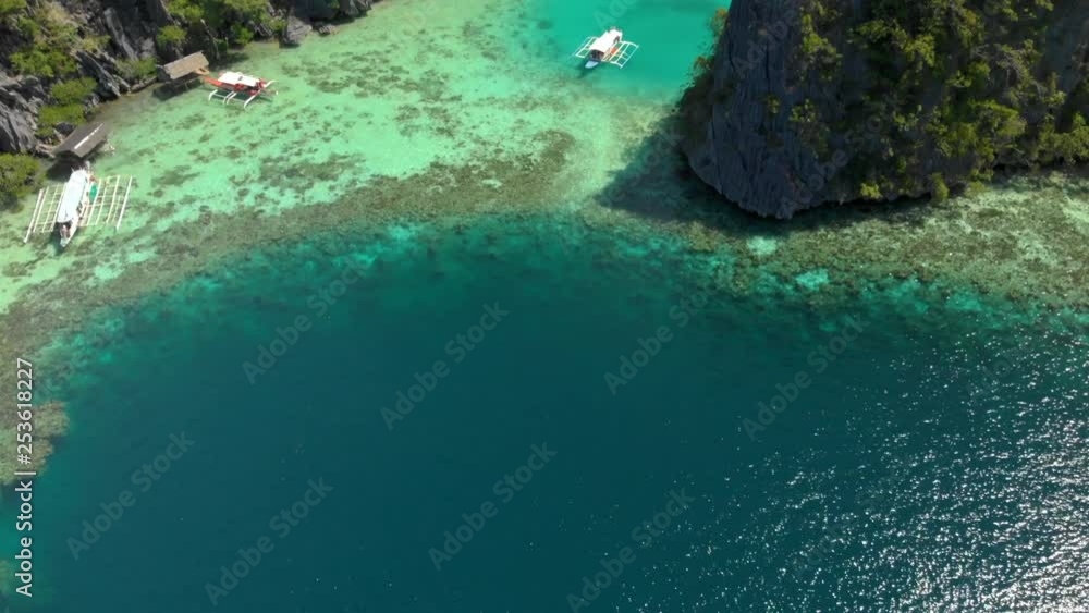 Beautiful mountain landscape and dense rainforest of Busuanga, Philippines. TILT DOWN reveals a shallow cove with several traditional boats called vancas. Clear blue water in a tropical paradise. Beautiful mountain landscape and dense rainforest of Busuanga, Philippines. TILT DOWN reveals a shallow cove with several traditional boats called vancas. Clear blue water in a tropical paradise.