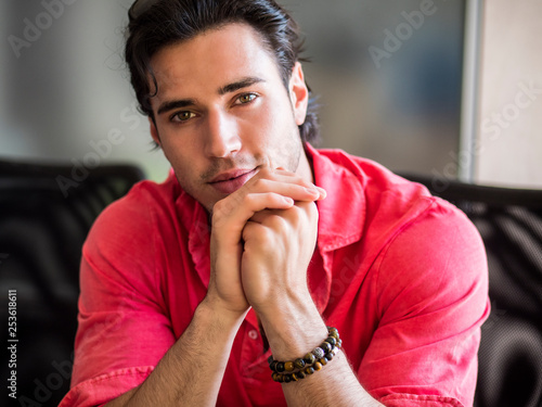 Obraz na plátně Attractive young man indoors wearing a shirt and beaded bracelets
