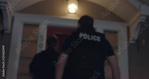 Police officers approach a house photo