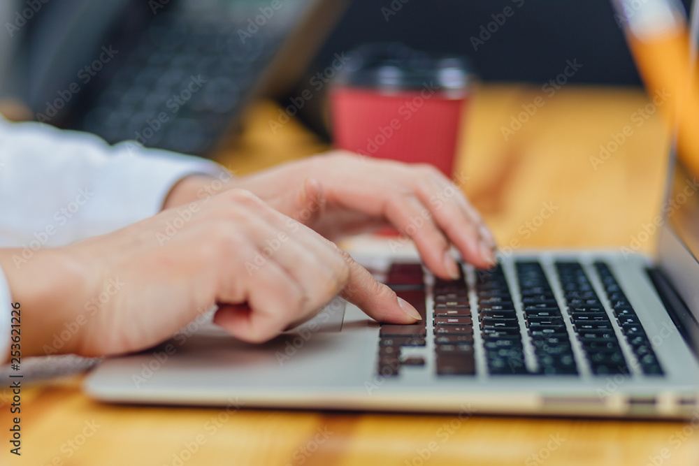 Holding a coffee young business girl working for a laptop. Lifestyle from a modern business woman using a laptop. Women's hands are working on reading an online website. Business Concept. During this Holding a coffee young business girl working for a laptop. Lifestyle from a modern business woman using a laptop. Women's hands are working on reading an online website. Business Concept. During this