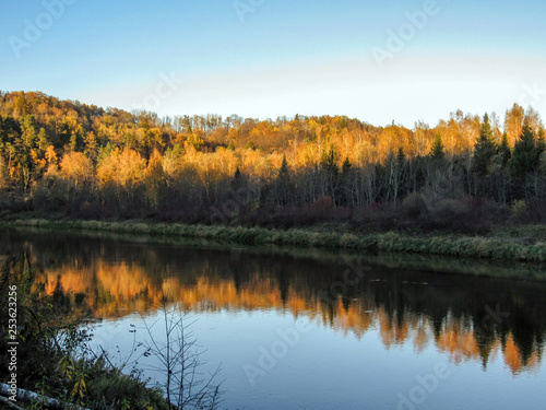 Sandstone outcrops, cliffs, rocks and caves along steep Gauja river banks and autumn colored trees reflections