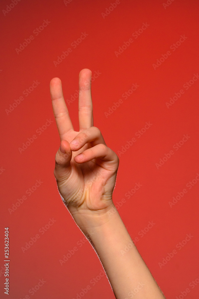 The soft hand showing the victory sign is isolated on a red background