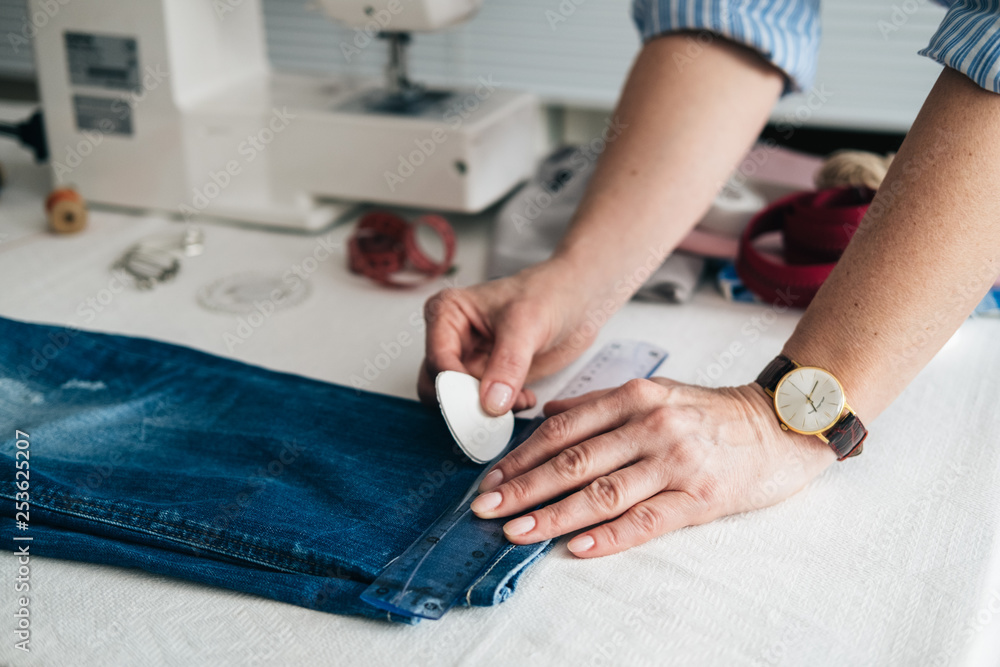 Seamstress marking hem on a pair of jeans in tailor shop Seamstress marking hem on a pair of jeans in tailor shop