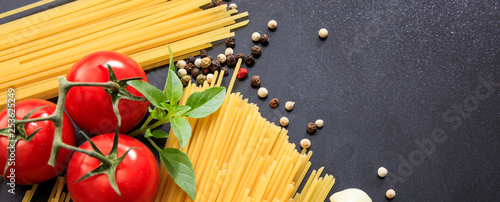 Spaghetti pasta, tomatoes, garlic and basil on black background, banner